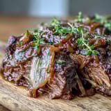 Slow-cooked Savory Crock Pot French Onion Pot Roast on a plate with onions and sauce.