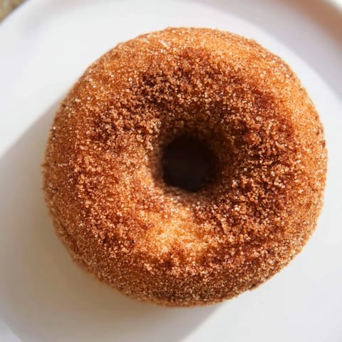 Warm, golden apple cider donuts with a glistening cinnamon sugar coating, ready to enjoy.