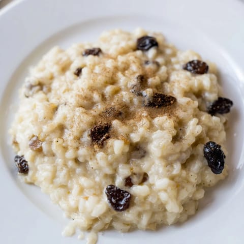 Thick and sweet rice pudding, brimming with plump raisins, is cooked to perfection in a baking dish.