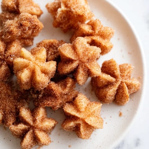 Crispy, sweet Churro Bites, perfect for sharing, stacked high and ready to enjoy with a warm drink.