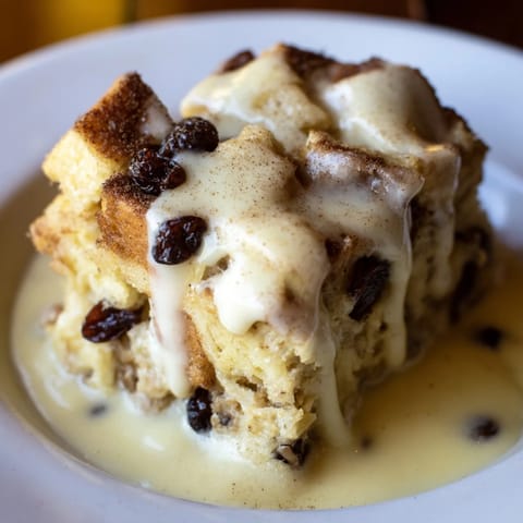 Golden baked bread pudding with a creamy sauce, perfect for a warming dessert.