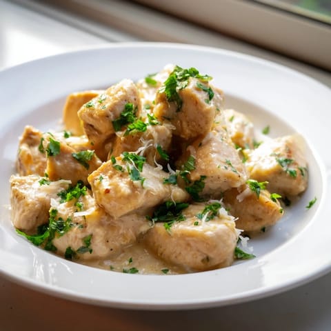 Tender Creamy Garlic Chicken Bites served over pasta with a side of steamed broccoli.