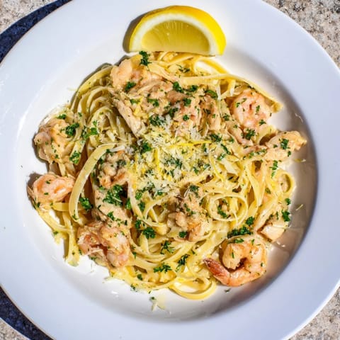 Fresh lemon wedges and chopped parsley garnish this hearty Italian-American surf-and-turf pasta, perfect for a weeknight dinner.