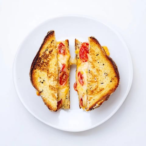 Golden-brown Pepper Jack & Tomato Grilled Cheese oozes spicy, melty cheese, served fresh and hot on a rustic plate.  