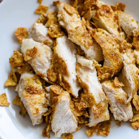 Crunchy Taco Chicken Salad topped with shredded cheddar, avocado slices, green onions, and a creamy lime-cumin dressing.