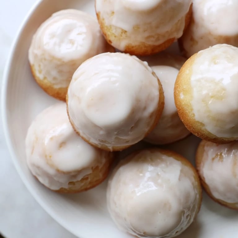 Freshly-baked muffin tin donuts, glistening with vanilla glaze, a delightful treat for any occasion.