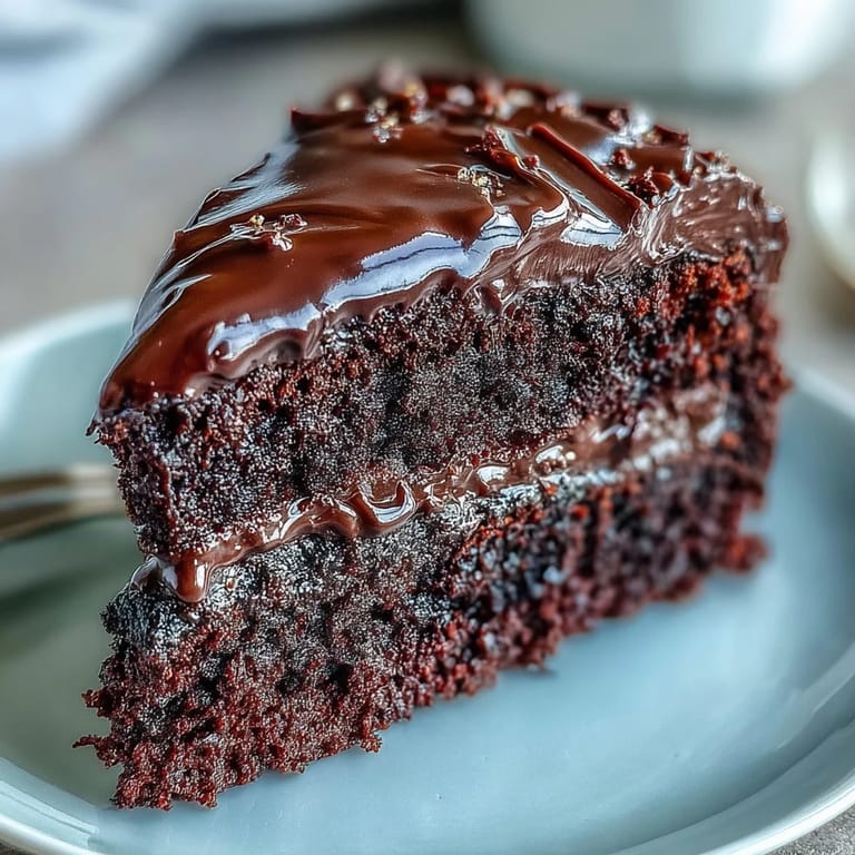 Easy Chocolate Fudge Cake with rich chocolate icing, sliced on a white plate.