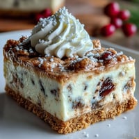 Christmas Cheesecake Slab squares topped with whipped cream and powdered sugar, served on a rustic wooden board for festive gatherings.