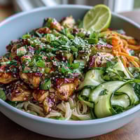 A colorful Asian Chicken Noodle Bowl with tender chicken, fresh vegetables, and a savory-sweet sauce in a vibrant bowl.  